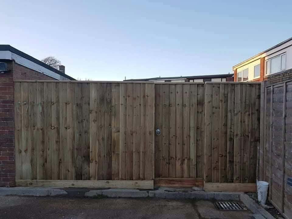 A tall close-board fence with matching double gates across the back of a yard