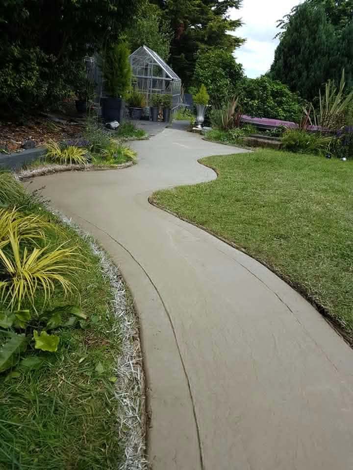 A smooth curving garden path through a lawn and planted borders