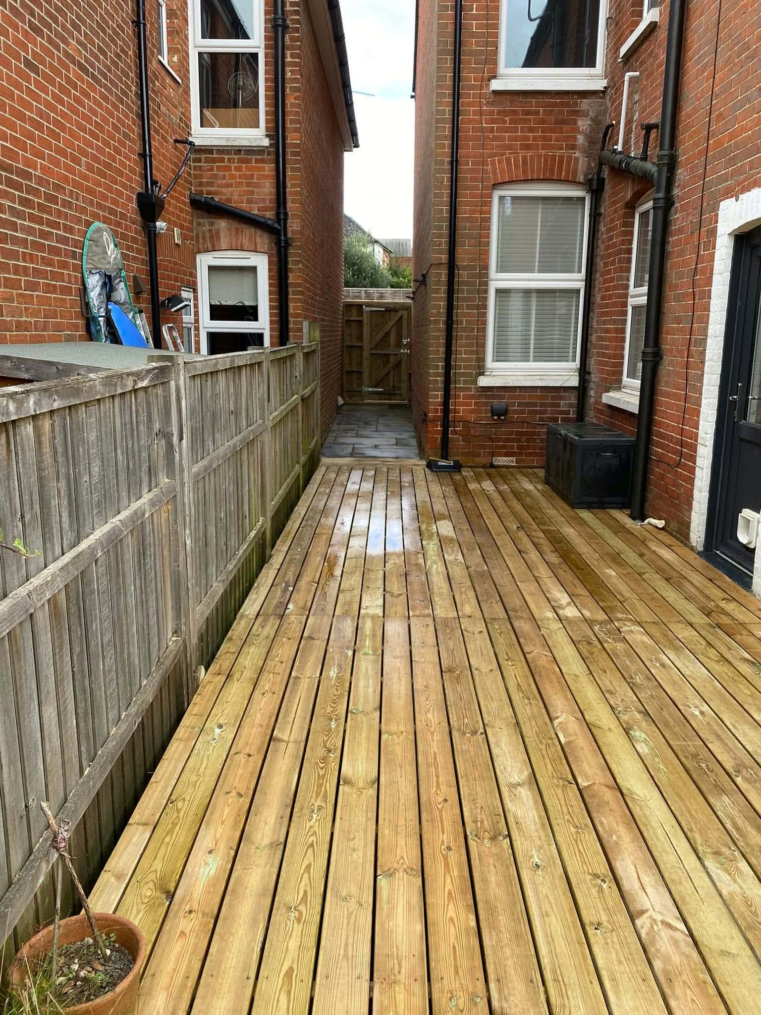 New timber decking running the length of a narrow side return beside a fence