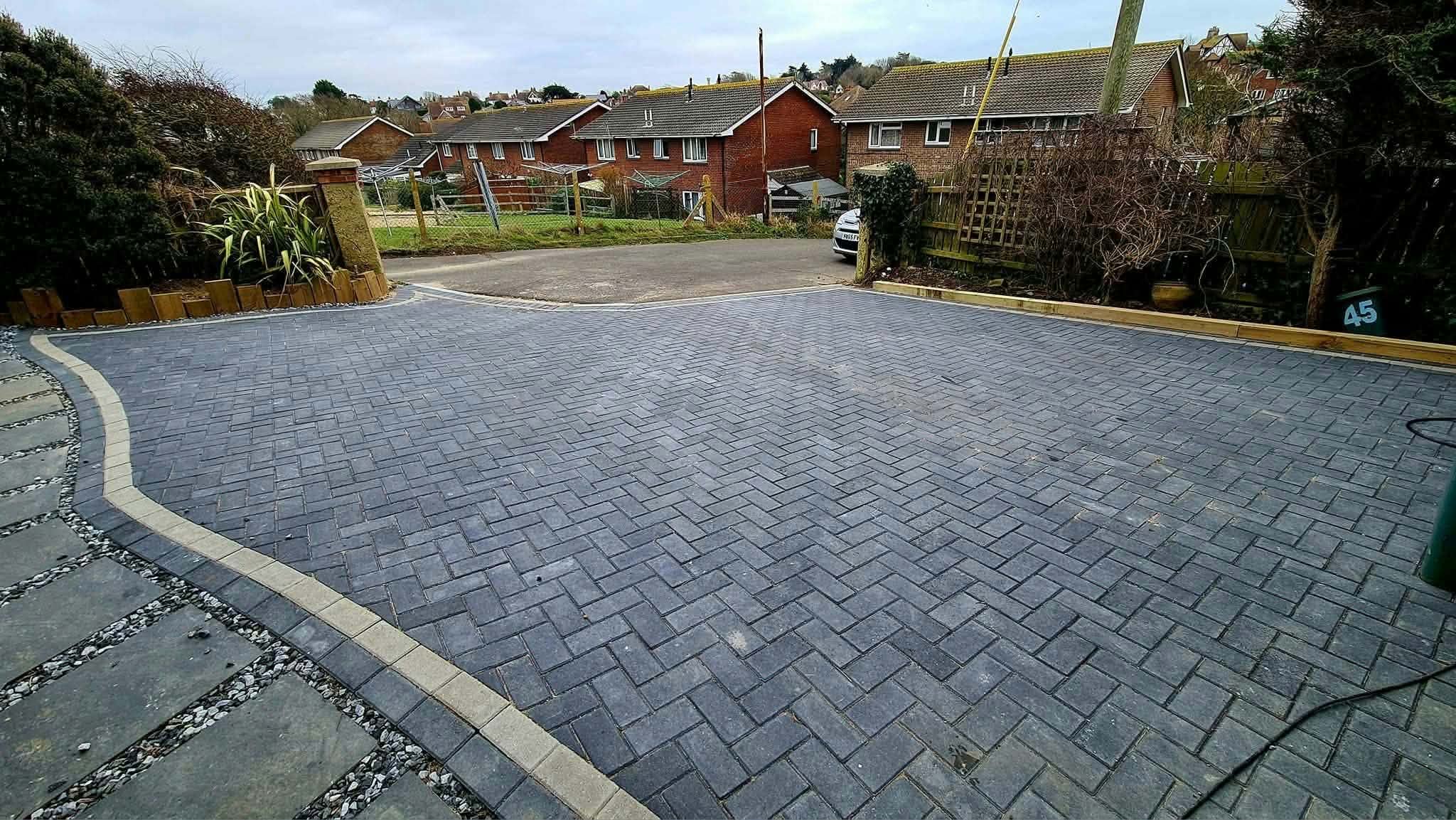 A new herringbone block-paved driveway with a curved light-coloured edge