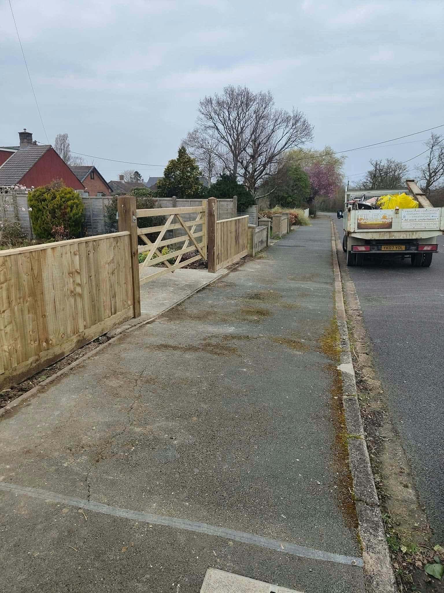 A wooden five-bar gate and close-board fence along a front boundary